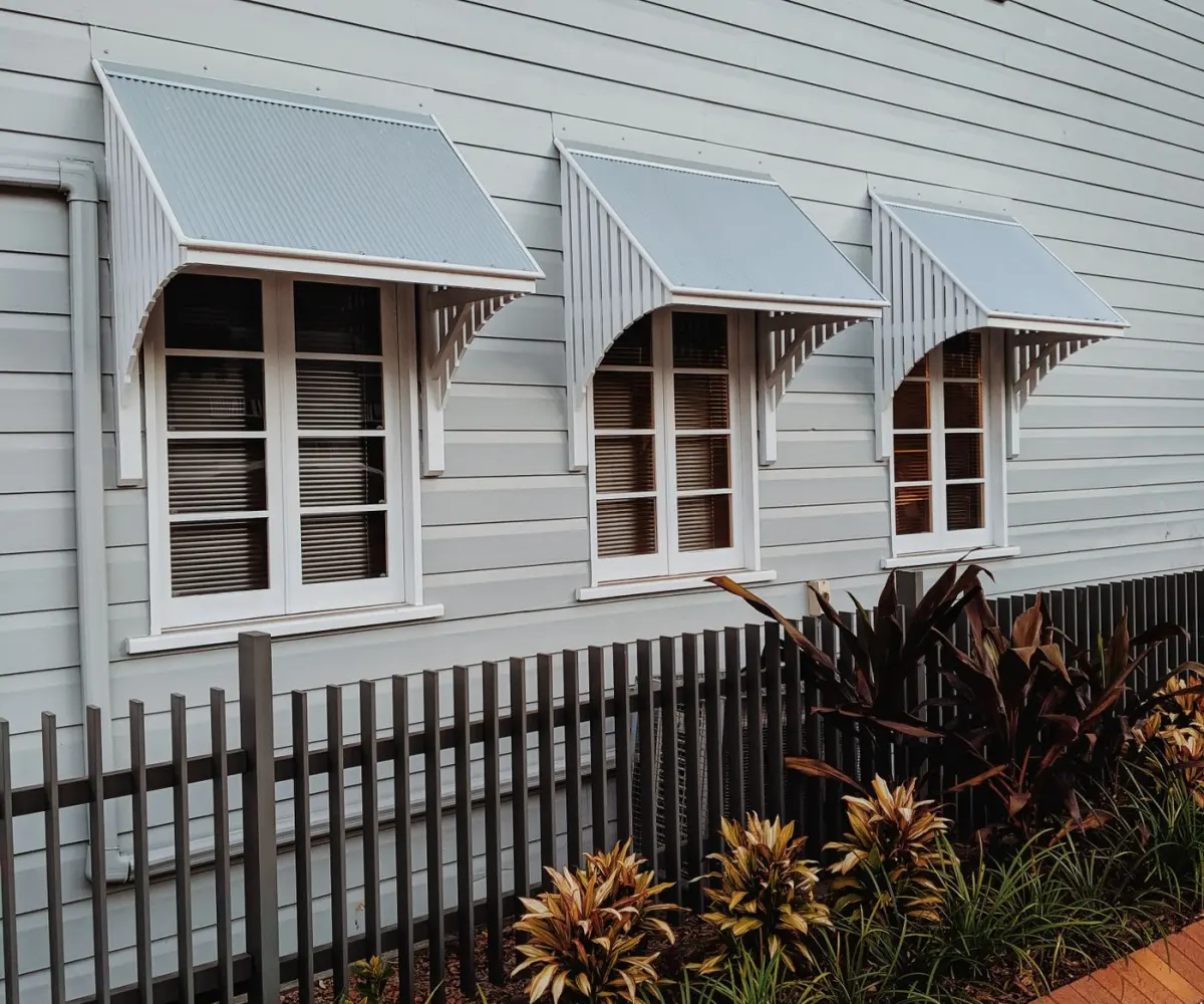 Weatherboard Queenslander home with window awnings and a tropical garden in Brisbane