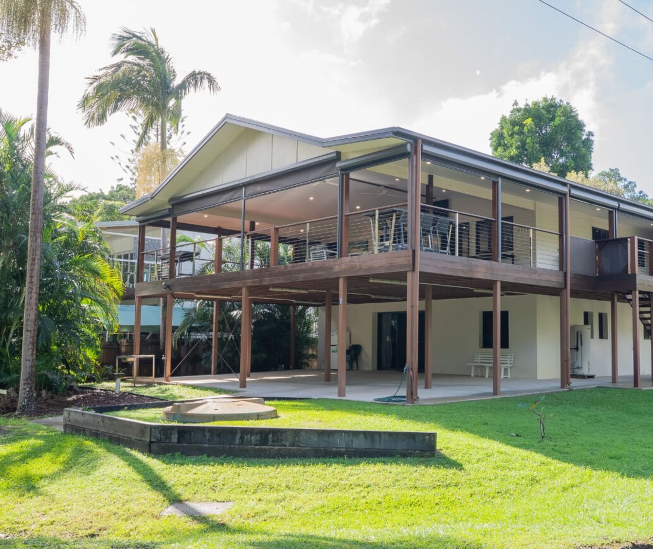 Elevated Queensland home with a timber deck, palms and a landscaped lawn on Stradbroke Island